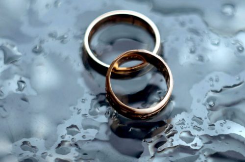 A pair of gold rings on a wet surface Description automatically generated