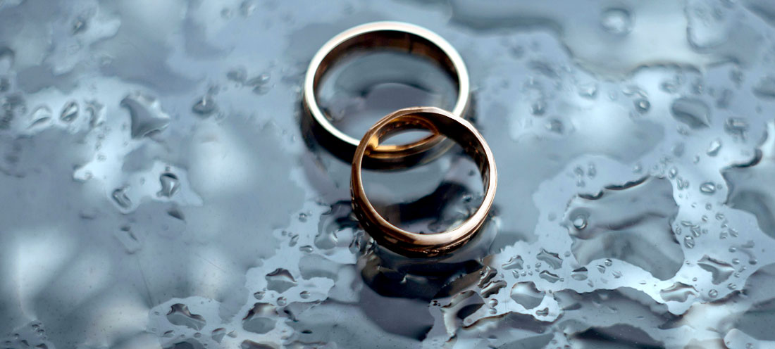 A pair of gold rings on a wet surface Description automatically generated