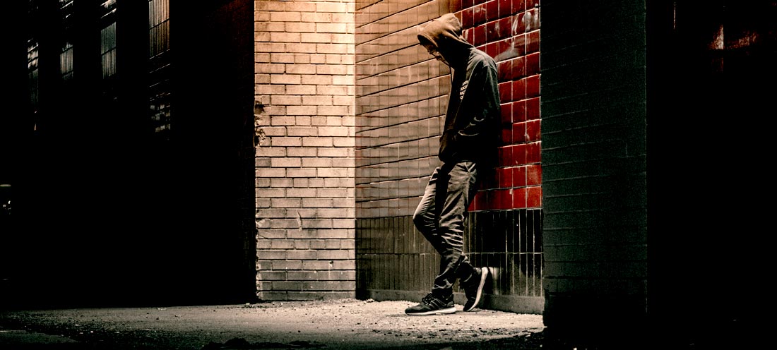 A person leaning against a brick wall

Description automatically generated