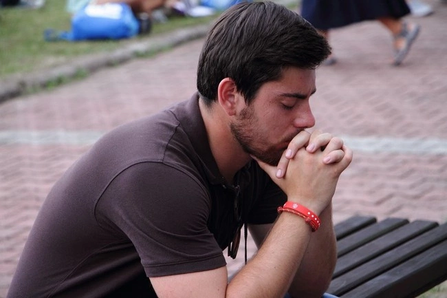 A person sitting on a bench with his hands in his mouth

AI-generated content may be incorrect.