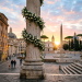 Decorated marble column with white flowers in a historic plaza at sunset